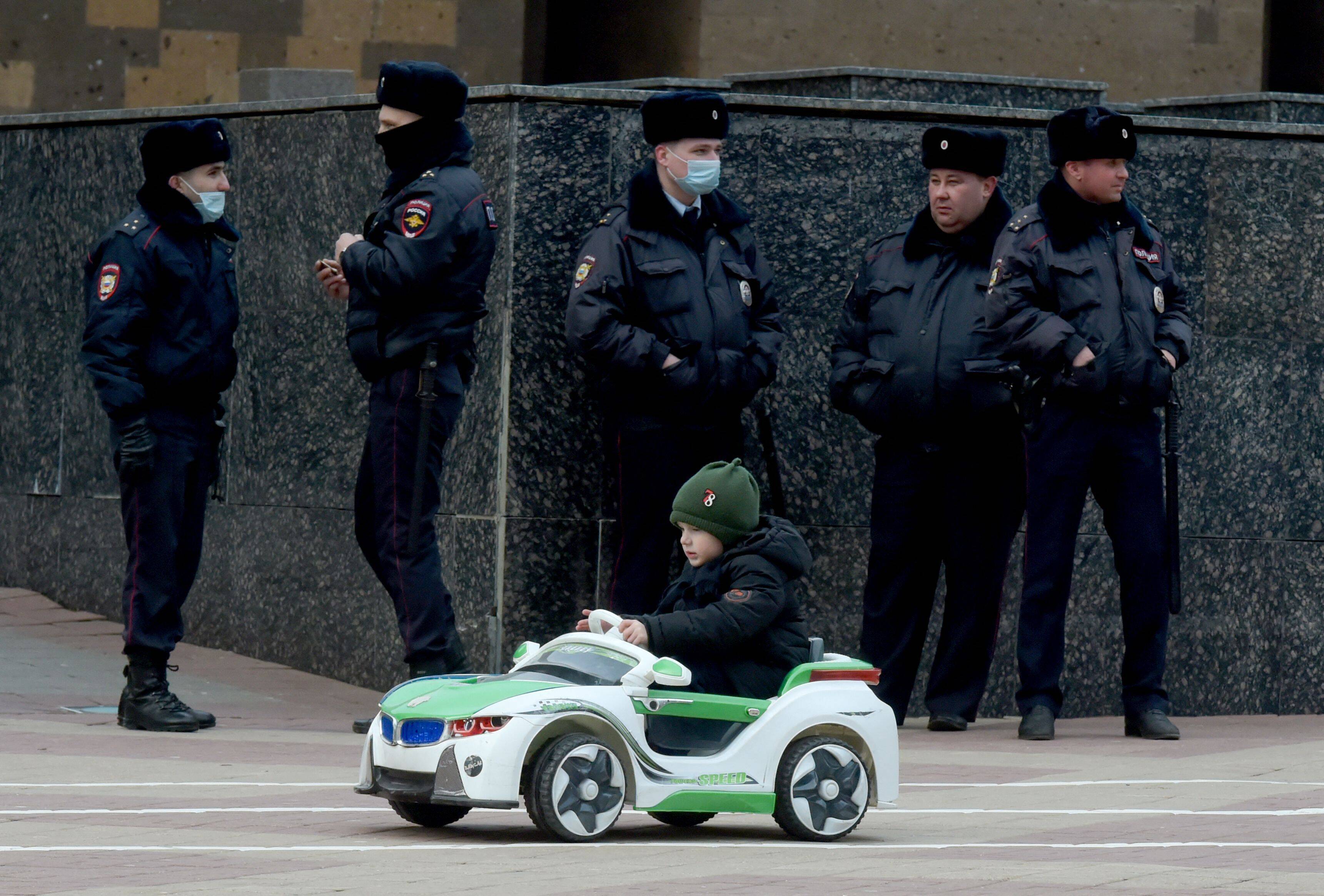 A child rides a toy car as police officers are seen deployed on the streets in the Russian Rostov region on Feb. 27, after calls for protests against Russia's invasion. (Stringer/AFP via Getty Images)