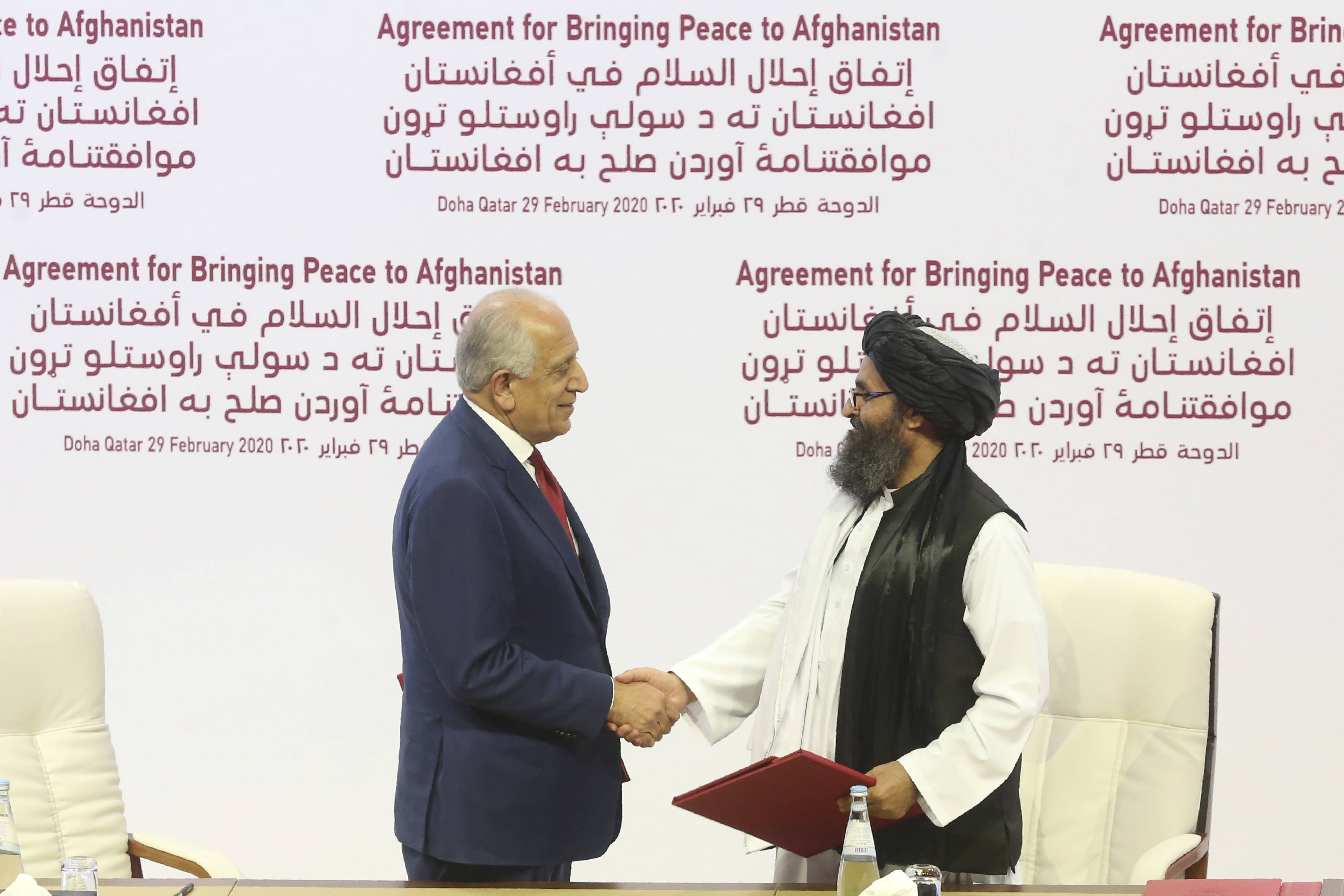 U.S. peace envoy Zalmay Khalilzad, left, and Mullah Abdul Ghani Baradar, of the Taliban shake hands in February 2020 as they sign a peace deal. (AP Photo/Hussein Sayed)