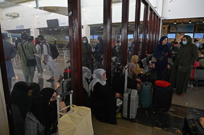 Passengers sit inside the departure terminal before boarding a Qatar Airways flight at the Kabul airport. (Wakil Kohsar/AFP)&nbsp;