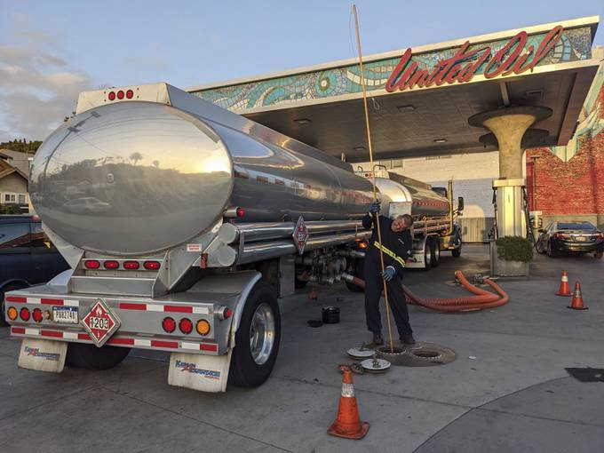 A fuel truck driver checks the gasoline tank level at a gas station in Los Angeles. (Damian Dovarganes/AP)