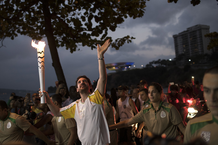 Leonardo Espindola carries the Olympic torch on its way to Rio&nbsp;for the opening ceremony&nbsp;in Niteroi, Brazil. (AP /Felipe Dana)</p>  