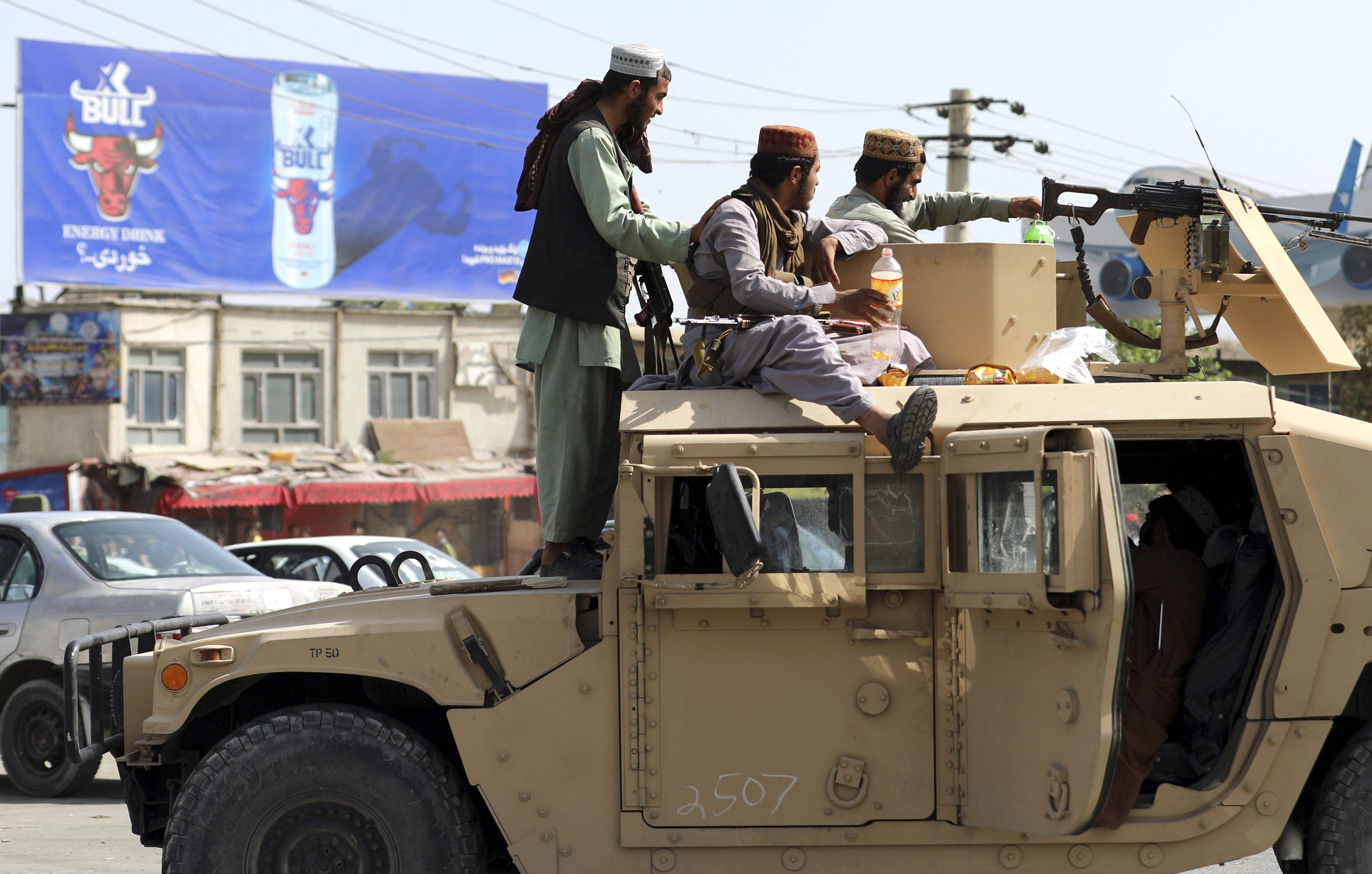Taliban fighters stand guard in front of the Hamid Karzai International Airport in Kabul, Afghanistan. (AP Photo/Rahmat Gul)