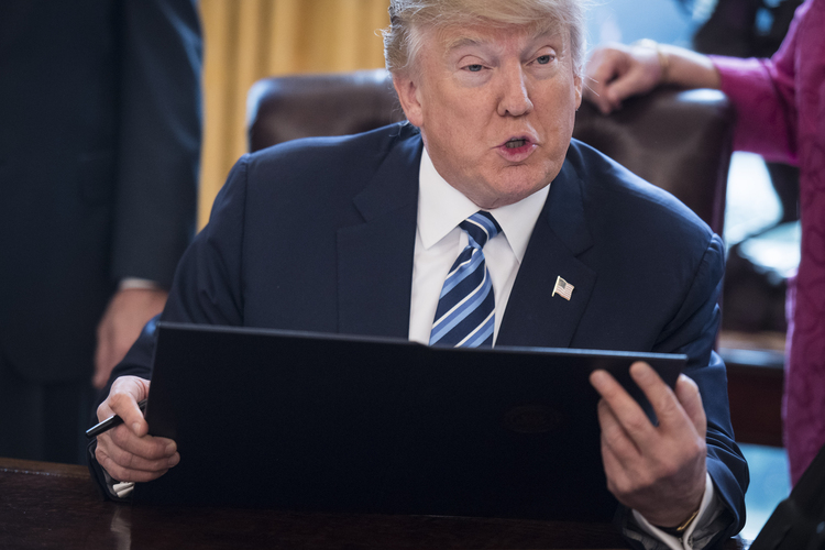 Trump signs one of three executive orders related to reducing crime in the Oval Office yesterday. (Jabin Botsford/The Washington Post)</p>