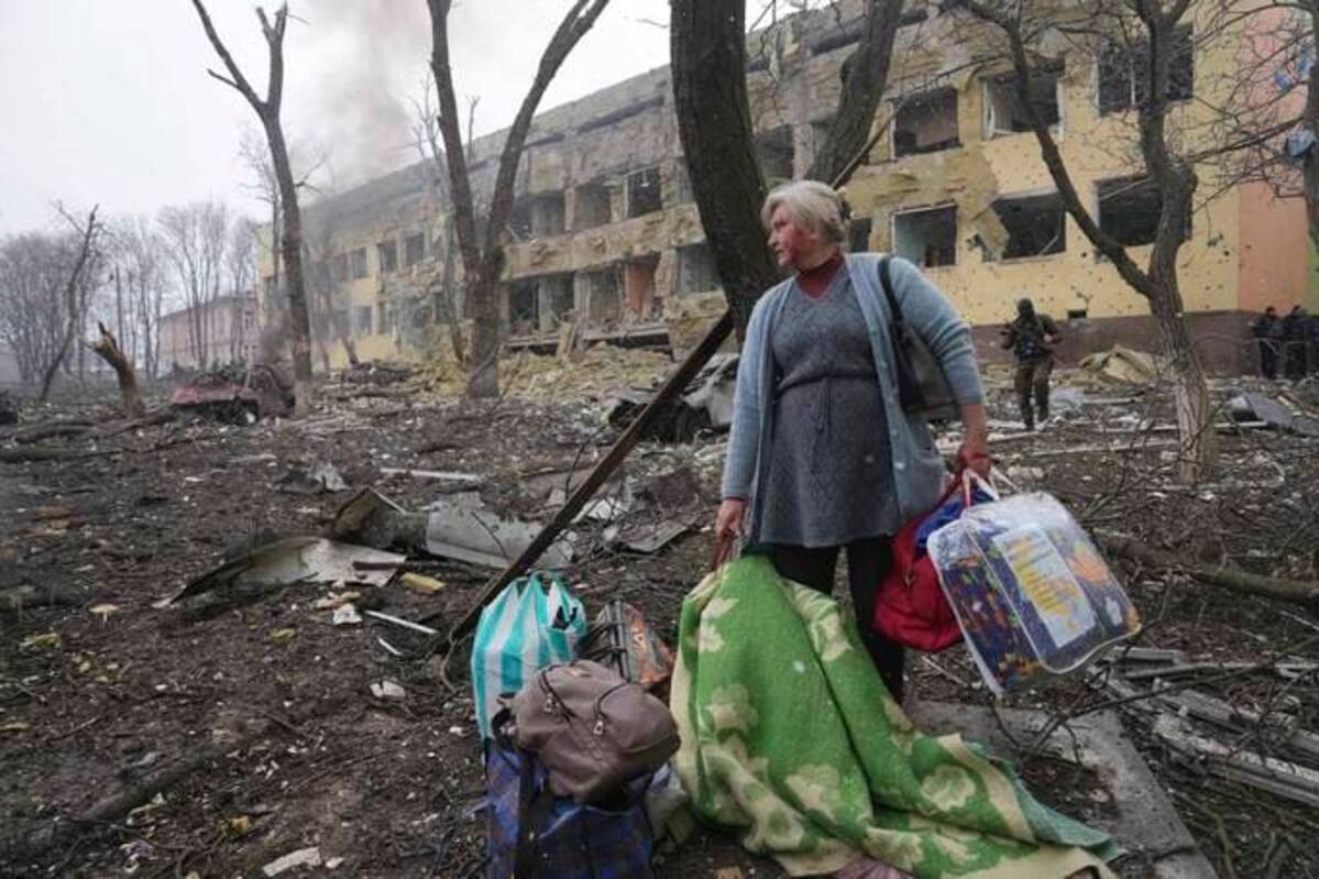 A woman walks outside a maternity hospital that was damaged by shelling in Mariupol, Ukraine, on Wednesday. (Evgeniy Maloletka/AP)