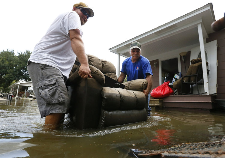 Residents carry damaged furniture through flood waters in Sorrento, Louisiana. (Reuters/Jonathan Bachman)</p>  