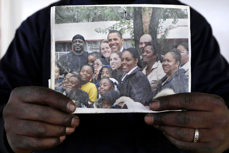 John Diggs, 48, holds a photo where he can be seen with Barack Obama during a visit to Lloyd Bond elementary school.&nbsp;Diggs is a janitor and security guard at the school.</p>  