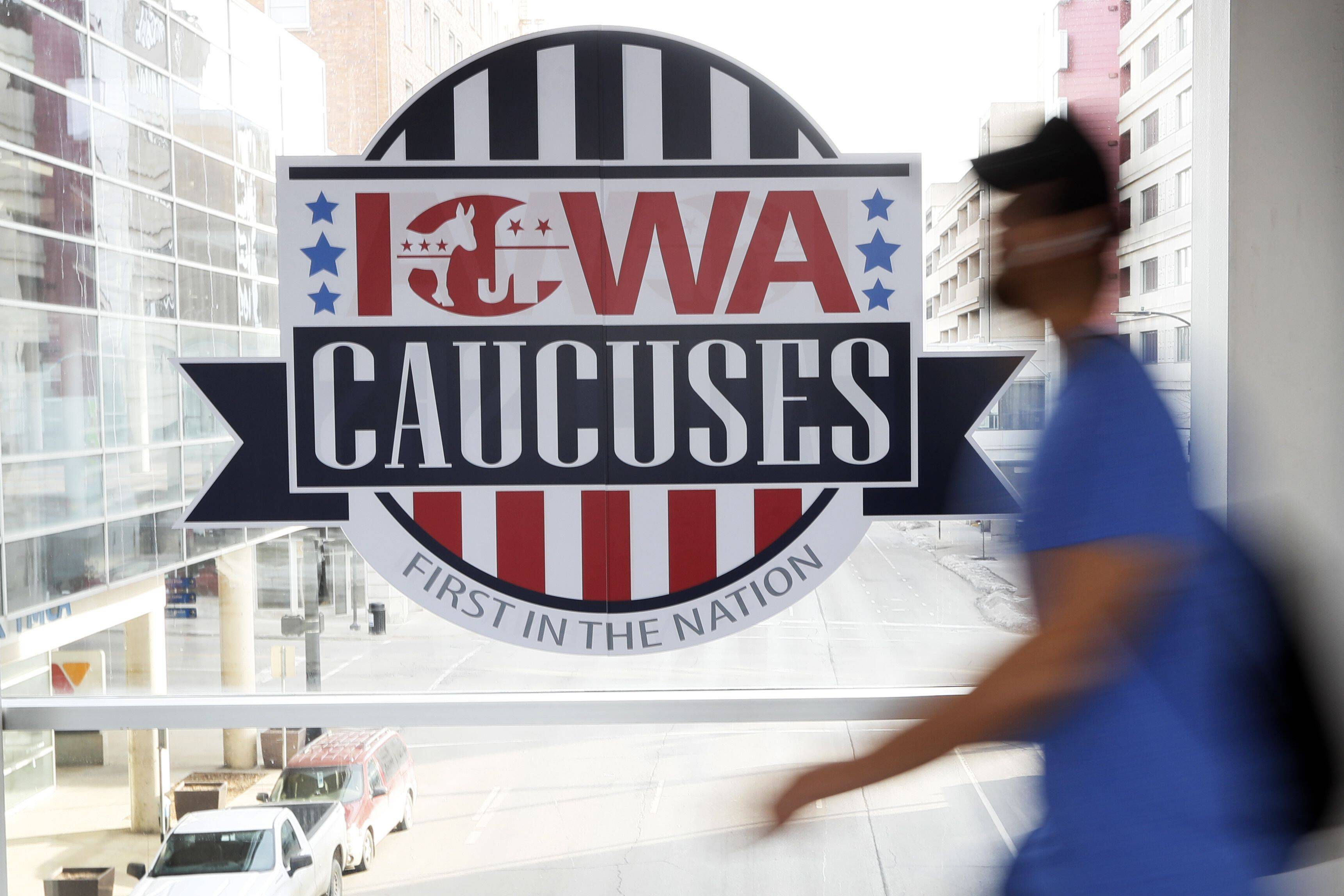 A pedestrian walks past a sign for the Iowa caucuses on a downtown skywalk in Des Moines, on Feb. 4, 2020. (Charlie Neibergall/AP)