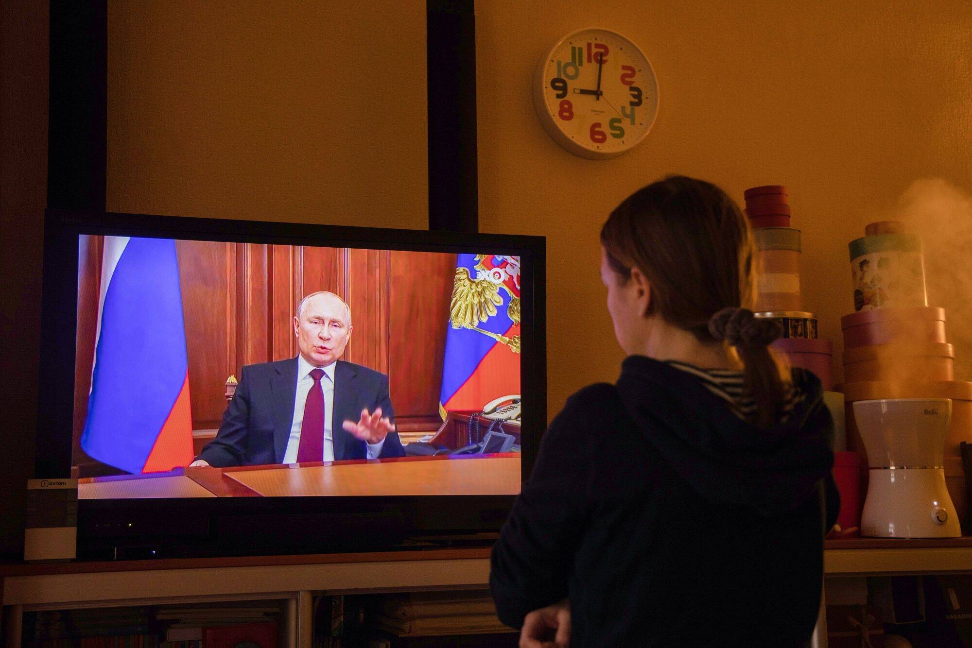 A resident in Moscow watches a live broadcast of Russian President Vladimir Putin as he delivers an address on Feb. 22. (Andrey Rudakov/Bloomberg)