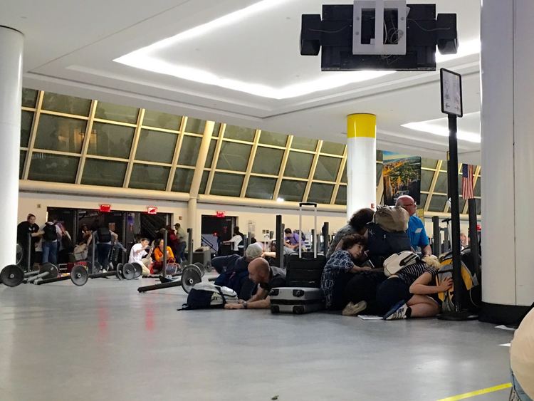 Passengers hide at immigration control during false reports of a shooter at JFK Airport. (AFP/Brigitte Dusseau)</p>