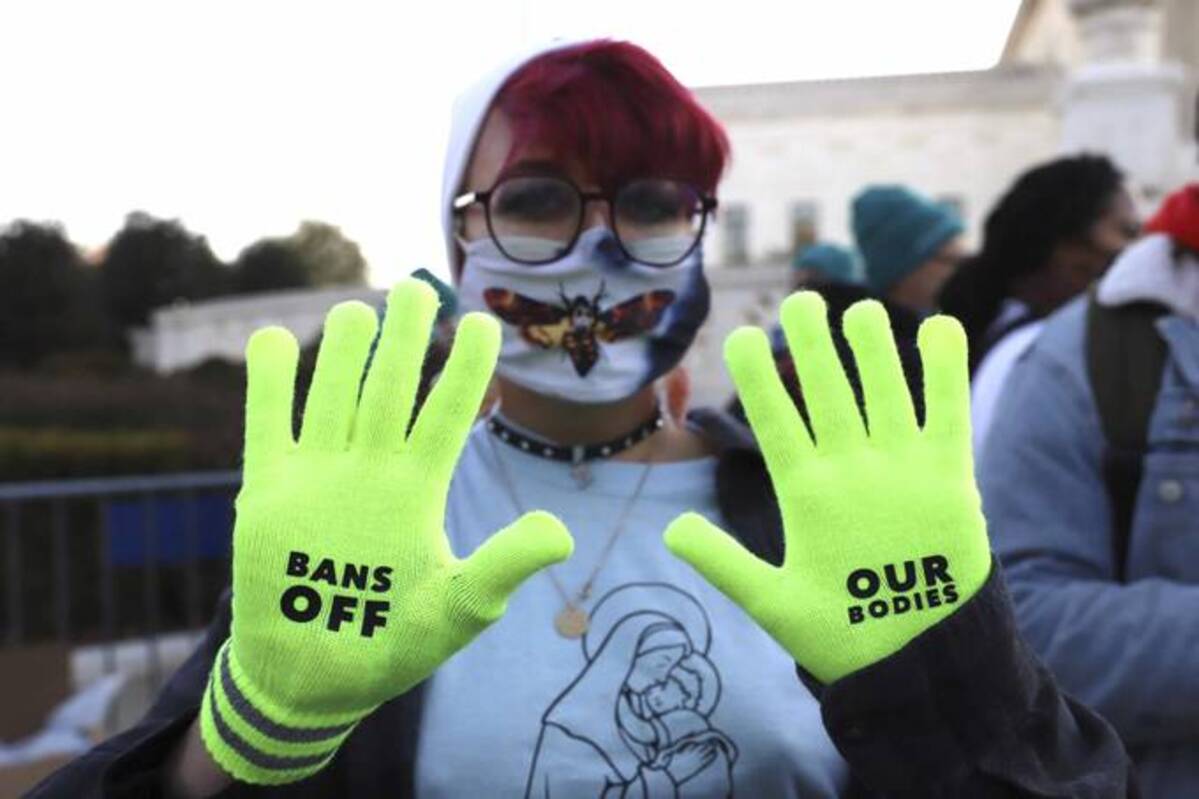 Jo Luttazi, 22, shows their hands with a protest message on their gloves outside the Supreme Court on Wednesday. (Parker Purifoy/AP)