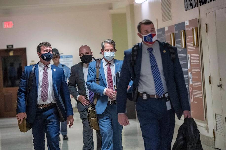 Georgia Gov. Brian Kemp (R), second from right, leaves the Georgia Capitol in Atlanta after signing a sweeping voting bill into law Thursday. (Alyssa Pointer/Atlanta Journal-Constitution/AP)