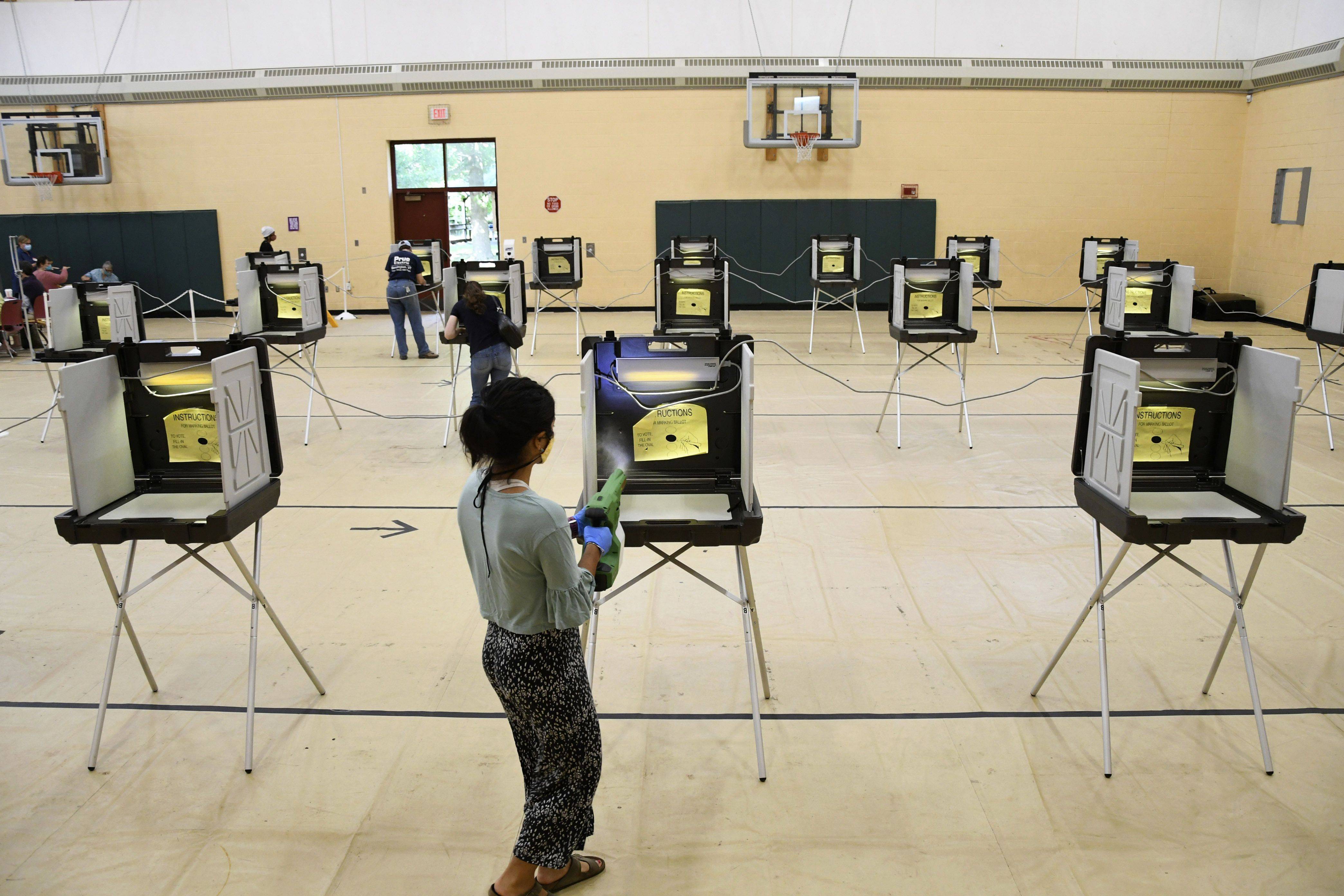 Williams College senior Niku Darafshi sanitizes voting booths in Williamstown, Mass., on Tuesday. (Gillian Jones/Berkshire Eagle/AP)