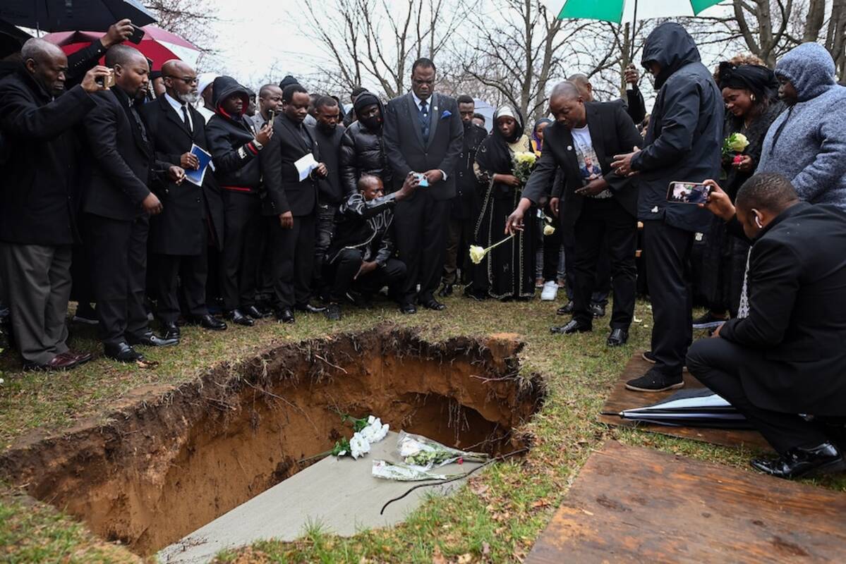 Patrick Lyoya's father, Peter, tosses a flower into his grave in the Grand Rapids, Mich., area on April 22. (Joshua Lott/The Washington Post)