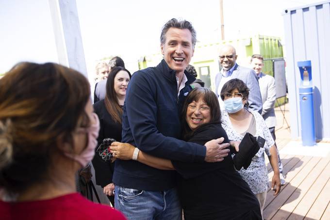 California Gov. Gavin Newsom receives a hug from Diane Jones, one of the residents at a newly opened interim homeless housing facility, during a news conference in Mountain View, Calif., on June 25. (Dai Sugano/Bay Area News Group/AP)