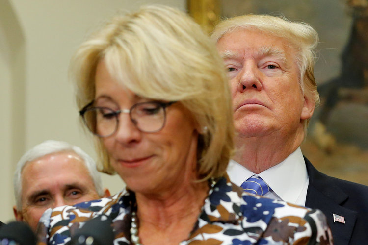 Donald Trump listens as Education Secretary Betsy DeVos speaks to students in May. (Jonathan Ernst/Reuters)  