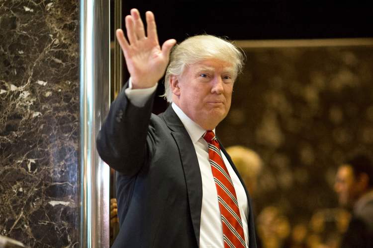 Donald Trump waves toward the media after meeting Martin Luther King III at Trump Tower yesterday. (Dominick Reuter/AFP/Getty Images)</p>  