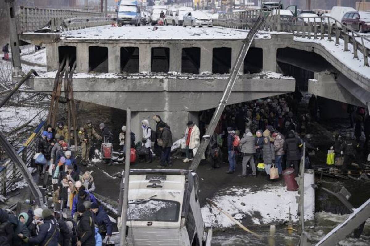 Abandoned vehicles of those who fled sit on the road before the destroyed bridge as people continue to leave the town of Irpin, on the outskirts of Kyiv, Ukraine on Tuesday. (AP Photo/Vadim Ghirda)