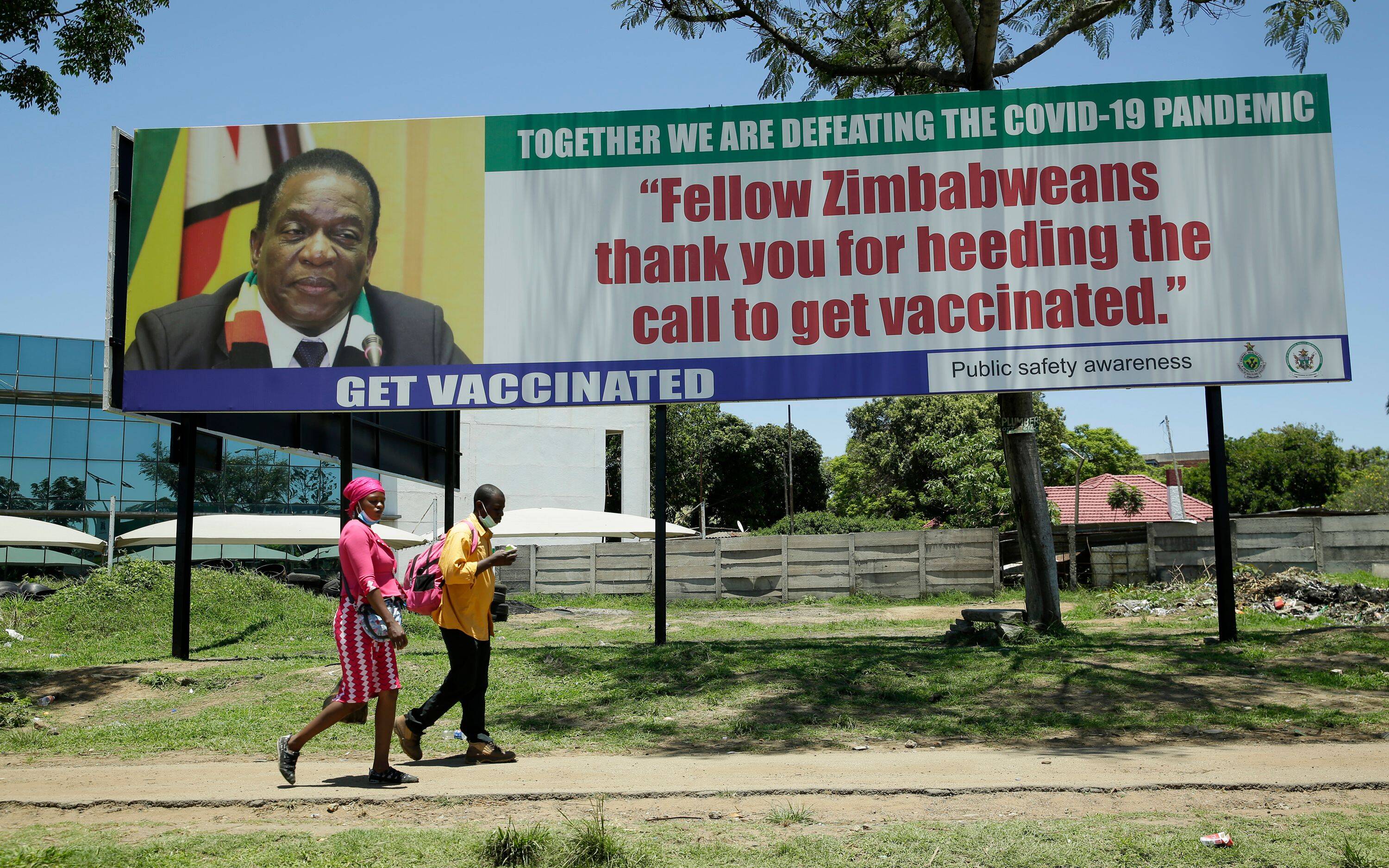 A couple walks past a billboard promoting vaccination in Harare, Zimbabwe, on Nov. 28. Zimbabwe faces travel restrictions due to the new coronavirus variant Omicron. (Aaron Ufumeli/EPA-EFE/REX/Shutterstock)