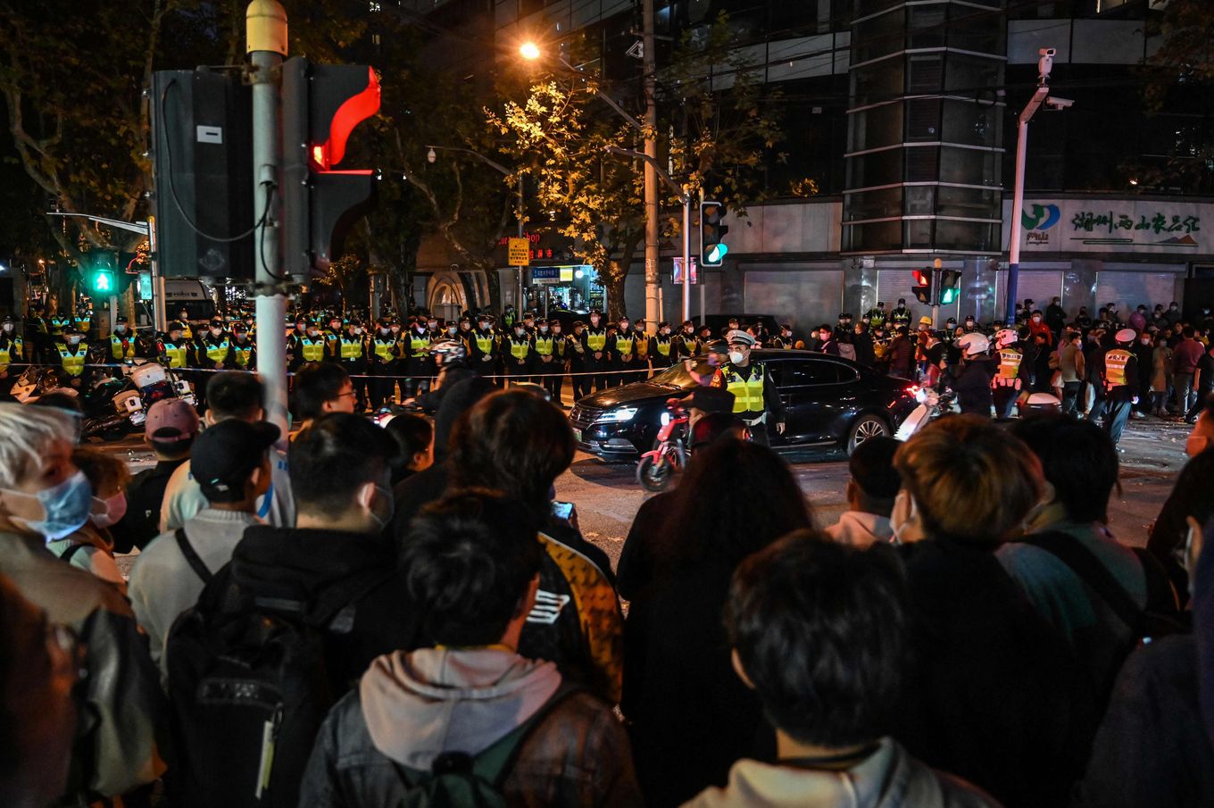 Police officers block Wulumuqi Road, named for Urumqi in Mandarin, amid protests in Shanghai on Sunday. (Hector Retamal/AFP/Getty Images)