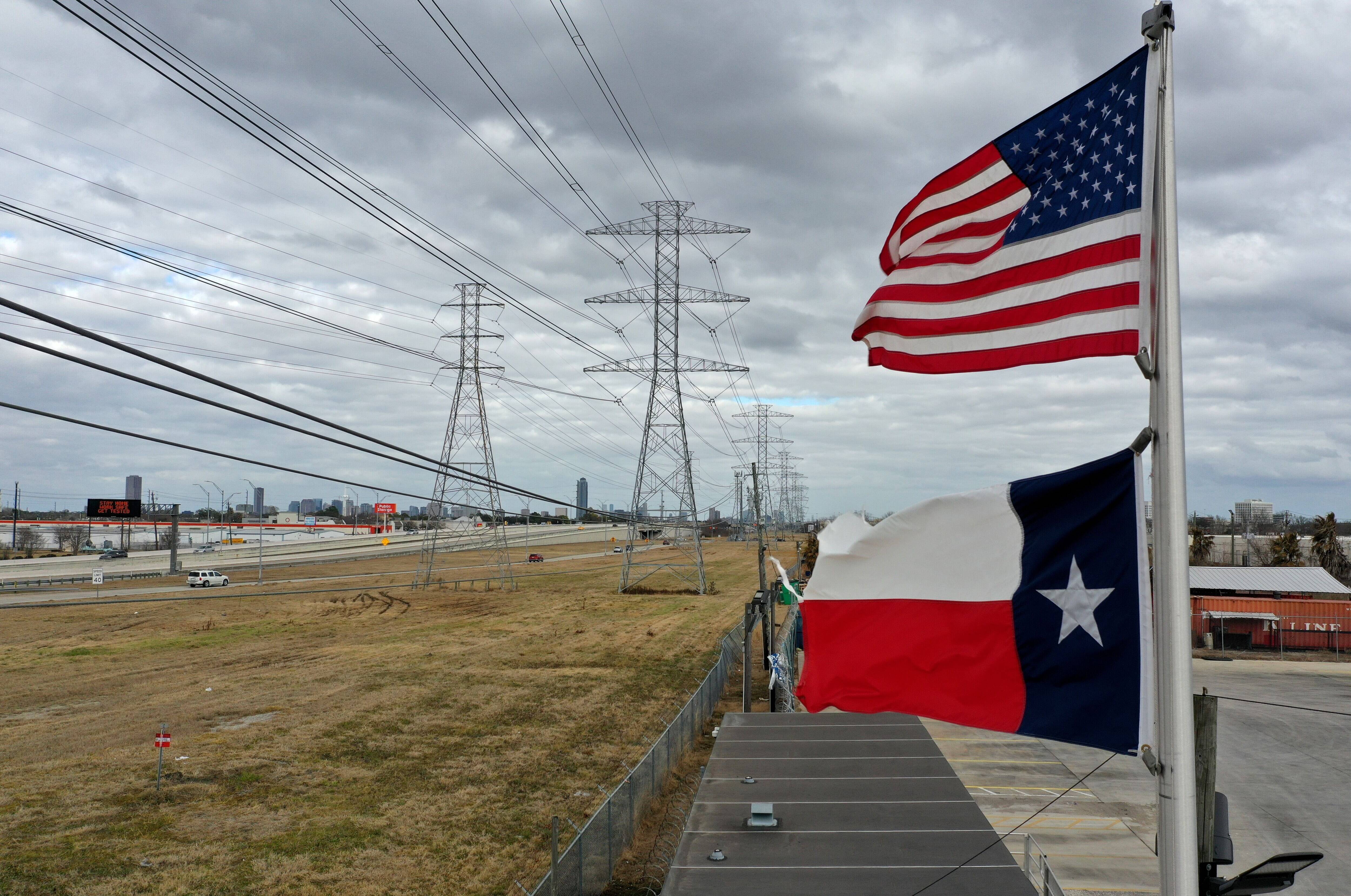 The U.S. and Texas flags fly in front of high voltage transmission towers on Feb. 21 in Houston. (Justin Sullivan/Getty Images)&nbsp;