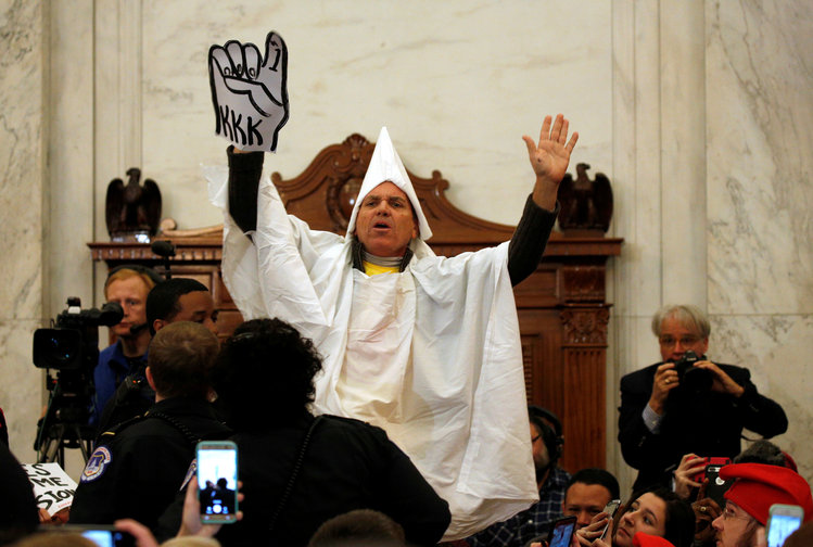 A protester dressed as Klansmen disrupts the Senate Judiciary Committee confirmation hearing for Sessions. (Kevin Lamarque/Reuters)</p>  