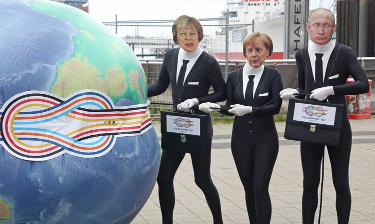 Activists dressed as Theresa May, Angela Merkel and Vladimir Putin squeeze an inflated globe during an event to protest the upcoming G20 summit. (Focke Strangmann/European Pressphoto Agency)</p>