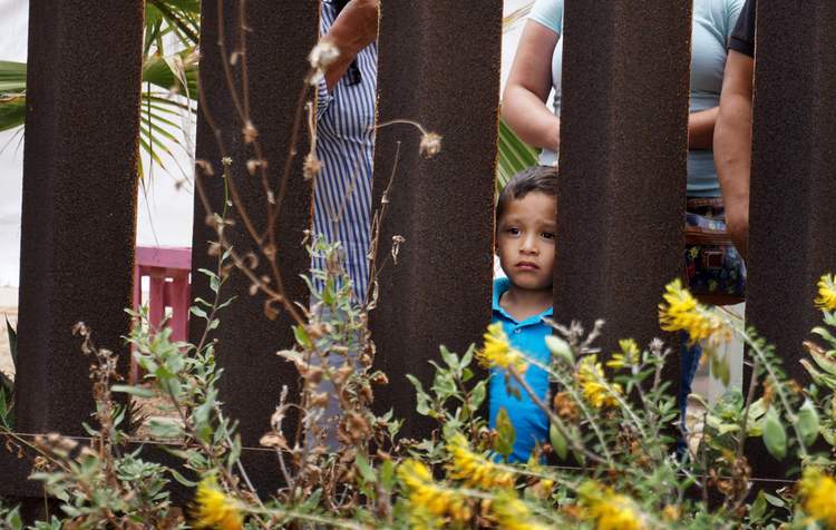 A child looks at family members through the U.S.-Mexico Border wall at Friendship Park in San Ysidro, California. (Sandy Huffaker/AFP)</p>