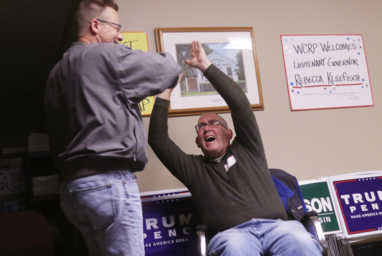 Mike Voss high-fives Jim Geldrich as they hear a television report projecting Trump winning Wisconsin in West Bend, Wis. (John Ehlke/West Bend Daily News via AP)</p>  