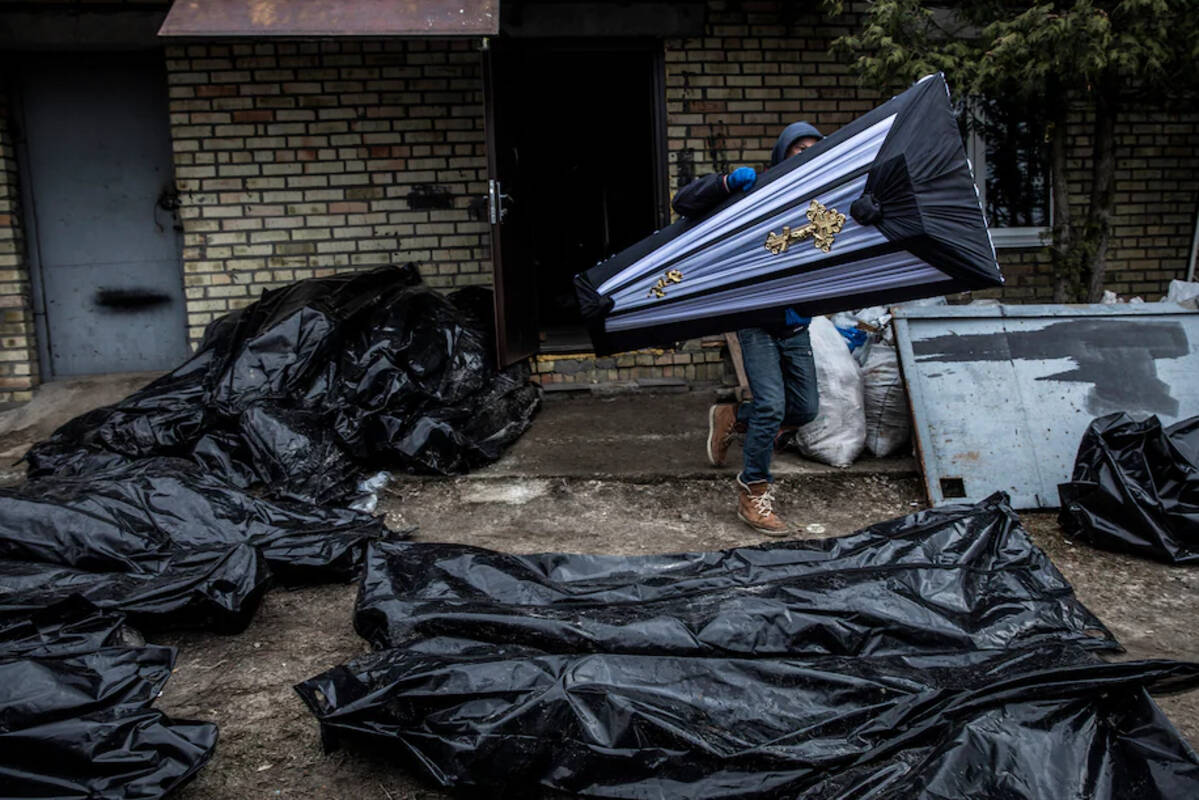 A man carries a coffin on April 6, as police officers investigate the killing of civilians in Bucha, Ukraine. (Heidi Levine for The Washington Post)