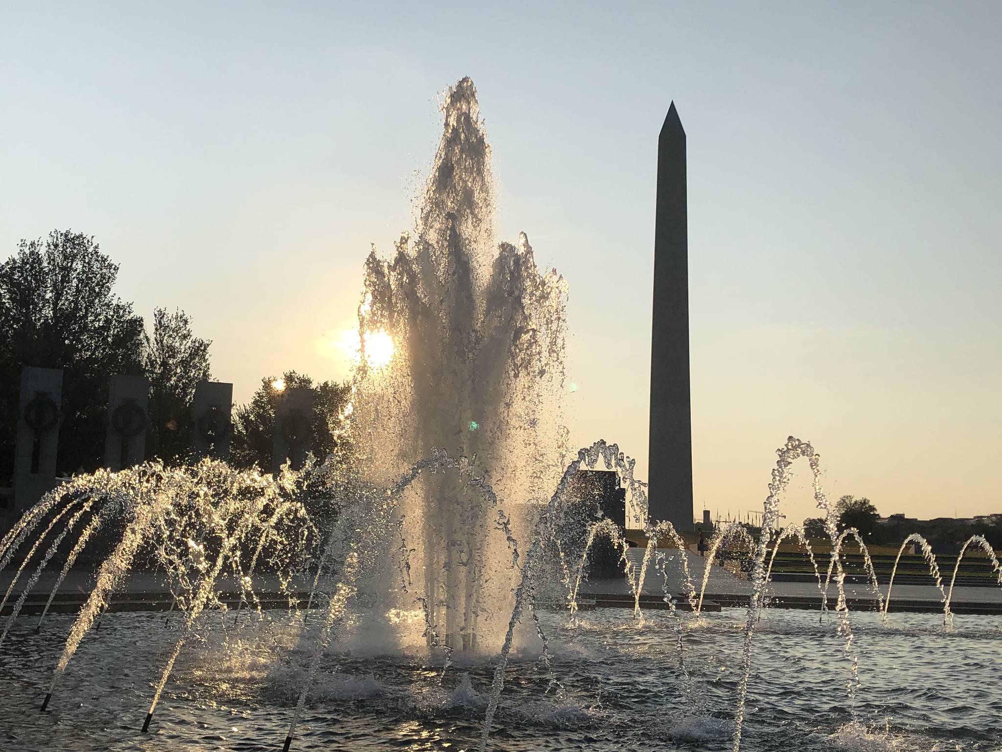 A hot day begins Thursday with sun rising behind the fountain at the National World War II Memorial in D.C.