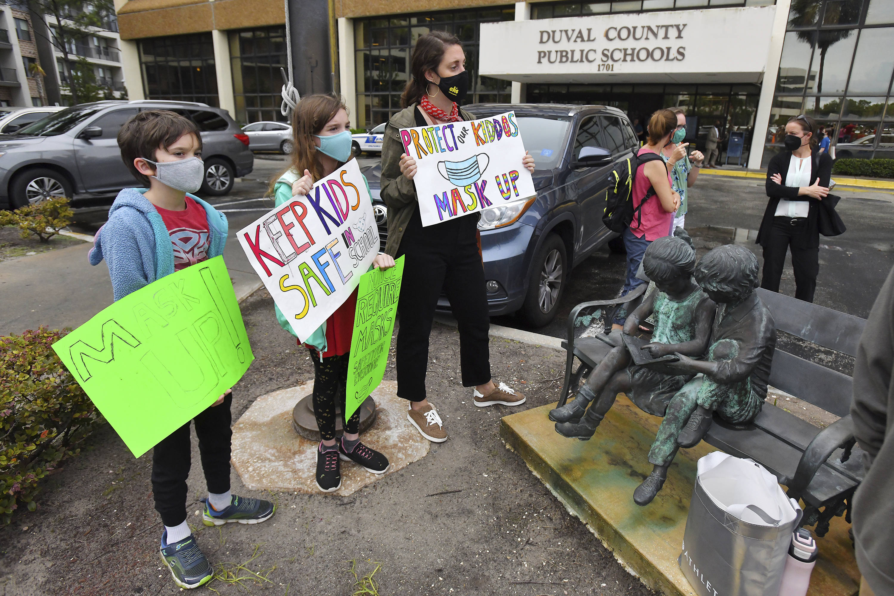Will Hartley, 10, Lila Hartley, 12, and Gabby Waxman hold their signs in support of masking in schools Tuesday before a school board meeting in Jacksonville, Fla. (Bob Self/The Florida Times-Union via AP)