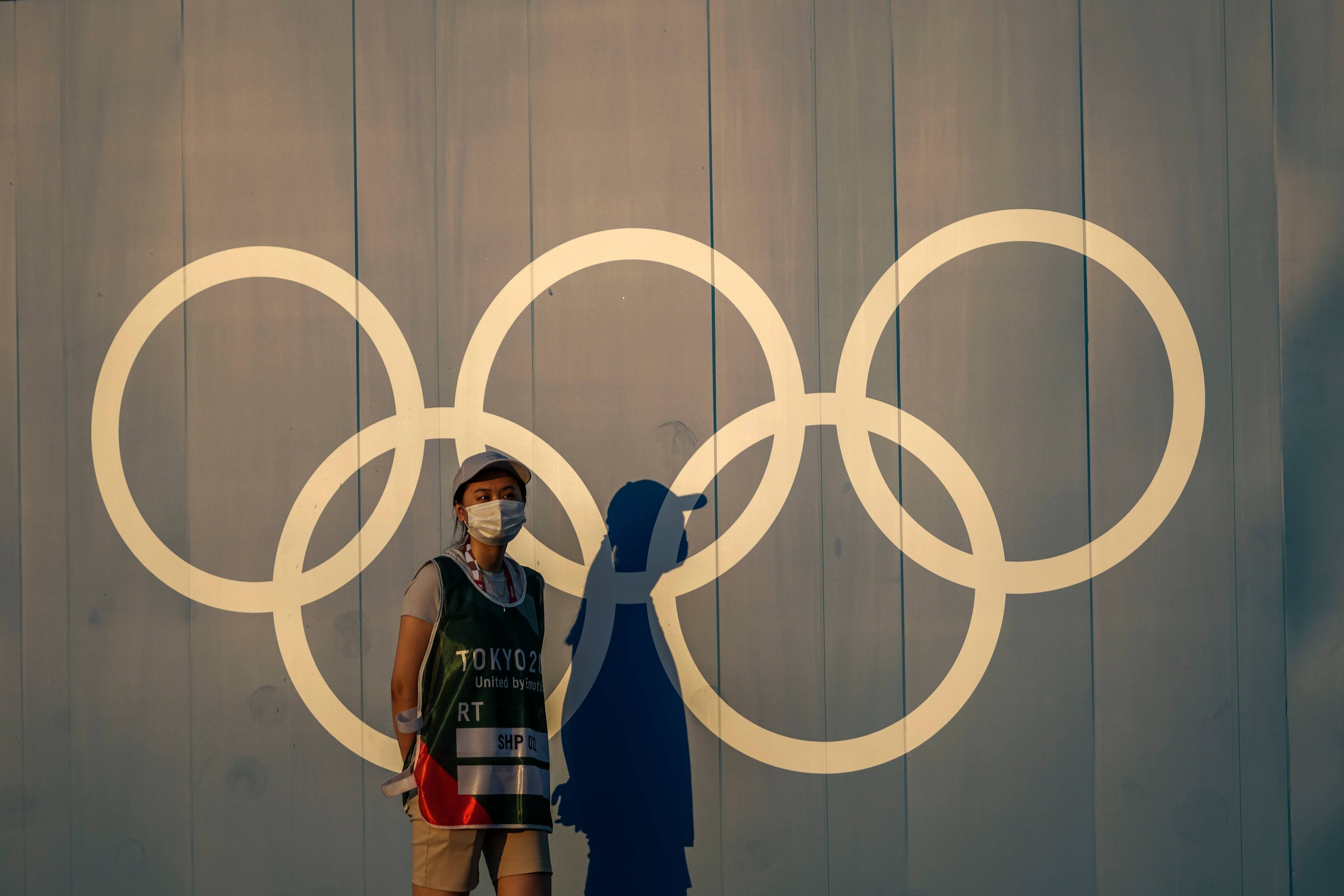 A volunteer walks past the Olympic rings. (Petros Giannakouris/AP Photo)