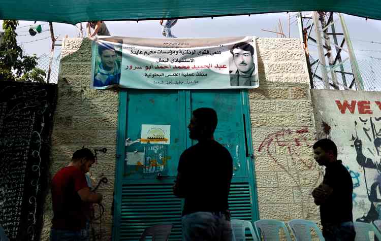 Palestinian youth stand next to a poster depicting a portrait of Abdel Hamid Abu Sorur at the Aida refugee camp in Bethlehem. The 19-year-old died last month after an explosive device blew up on a bus in Jerusalem. (Thomas Coex/AFP/Getty Images)</p>
