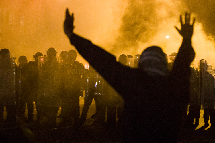 In April 2015, a protestor faces police using smoke grenades and pepper balls to&nbsp;enforce&nbsp;a curfew&nbsp;in Baltimore. (Matt Rourke/AP)</p>  