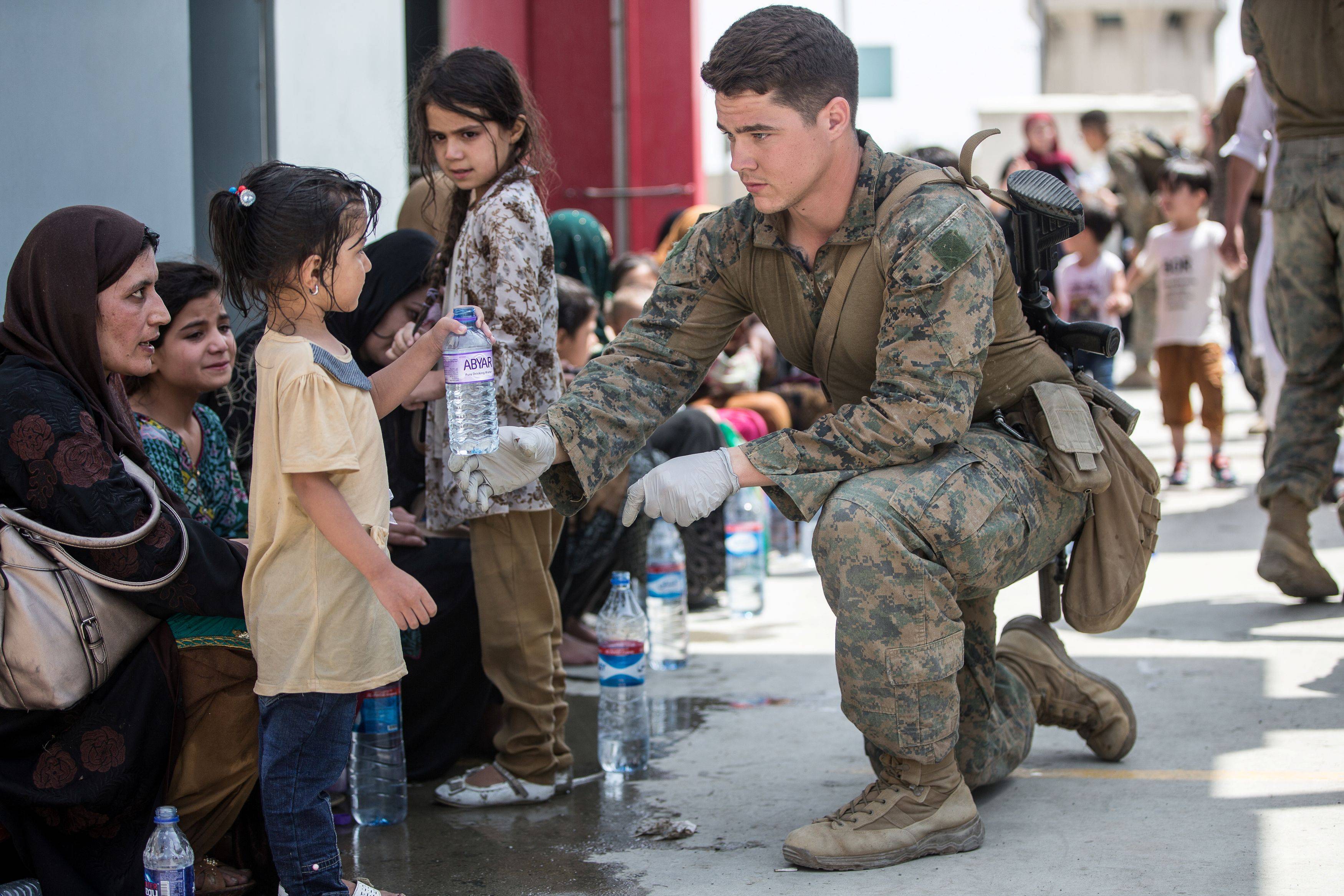 A Marine provides water to a child at the Kabul airport. (Sgt. Samuel Ruiz/U.S. Marine Corps/Handout)
