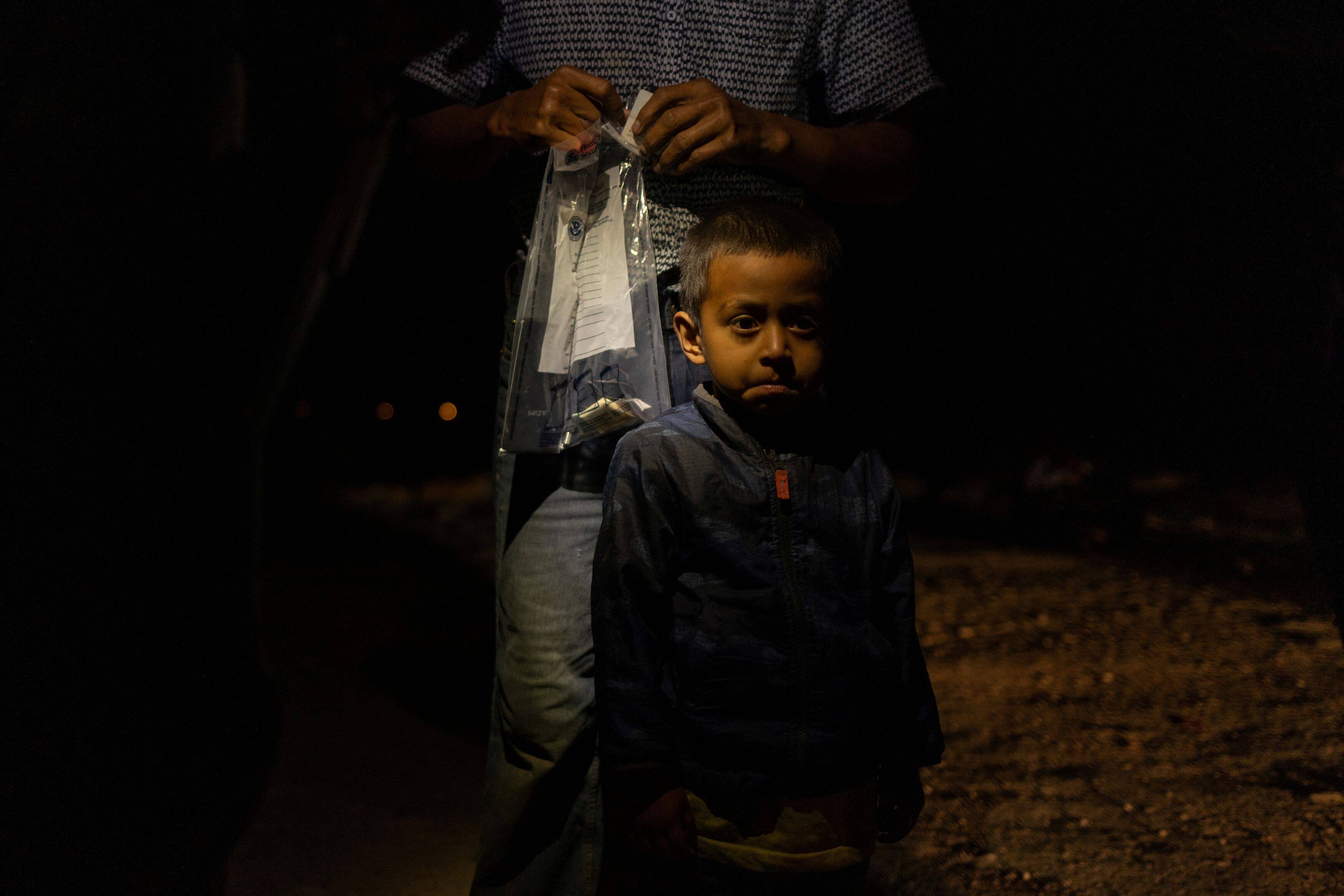 Jason, a 3-year-old migrant from Guatemala, stands next to his father as they are questioned by a Border Patrol agent on April 7 after crossing the Rio Grande from Mexico into the United States. (Adrees Latif/Reuters)