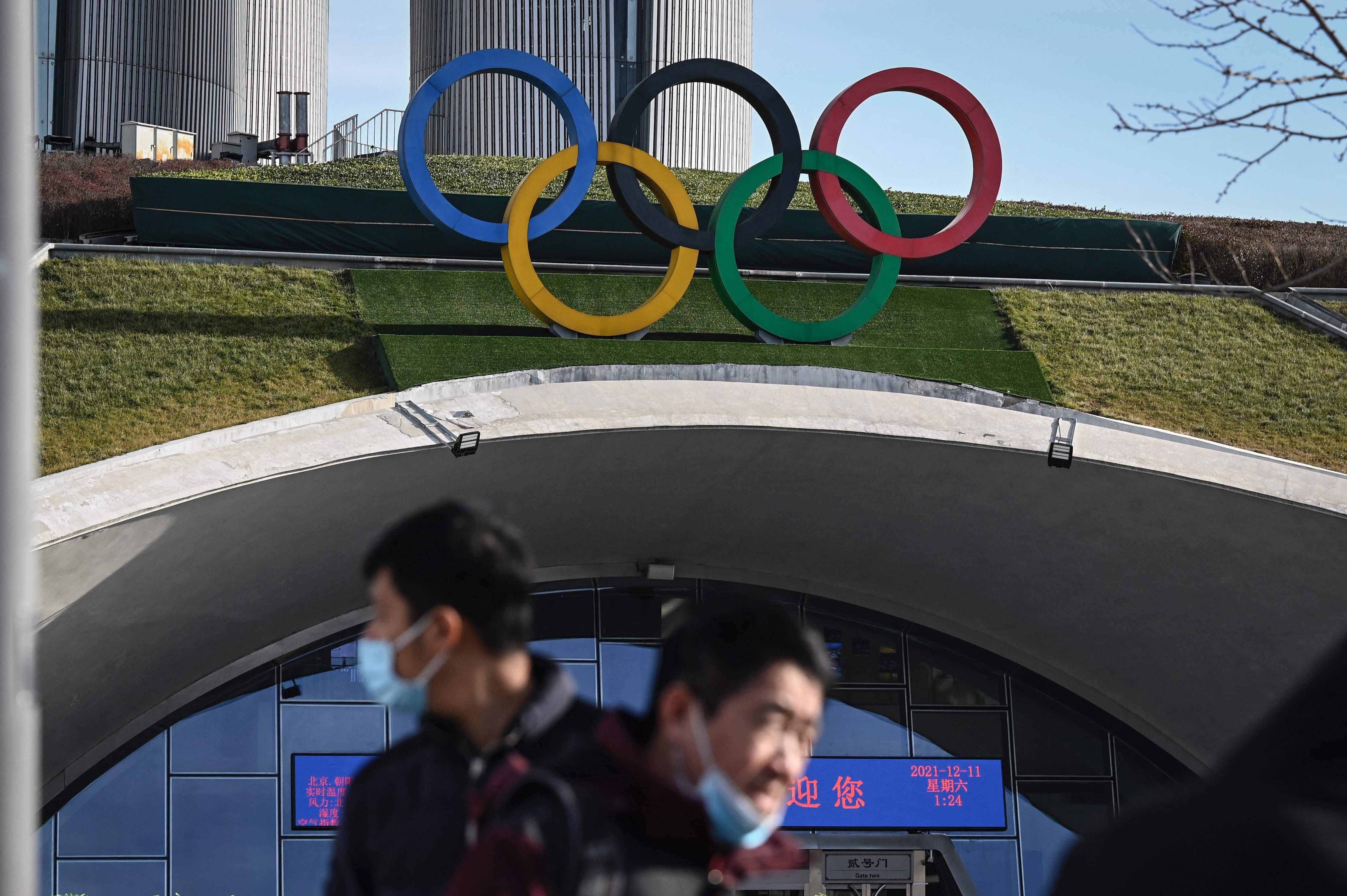 People walk in front of the Olympic rings at the Beijing Olympic Tower on Dec. 11. (Jade Gao/AFP via Getty Images)