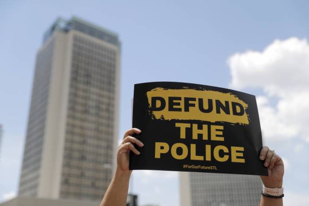 A person holds up a sign advocating for defunding the police as people gather to mark Juneteenth. (Jeff Roberson/AP)