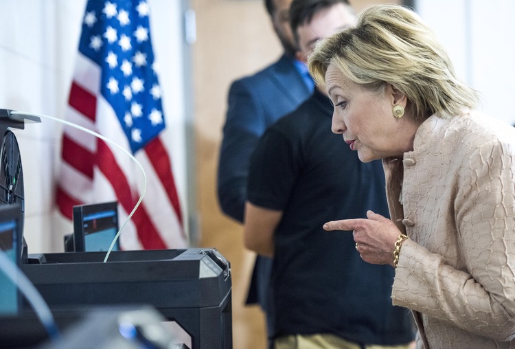 Clinton looks at a 3D printer while touring a high school classroom in Cleveland. (Melina Mara/The Washington Post)</p>  
