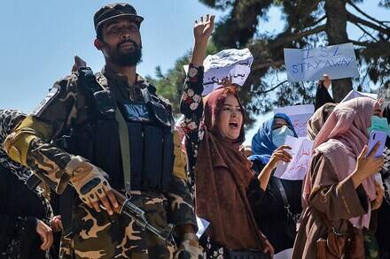 Afghan women shout next to a Taliban fighter during a protest near the Pakistani Embassy in Kabul on Tuesday. (Hoshang Hashimi/AFP/Getty Images)