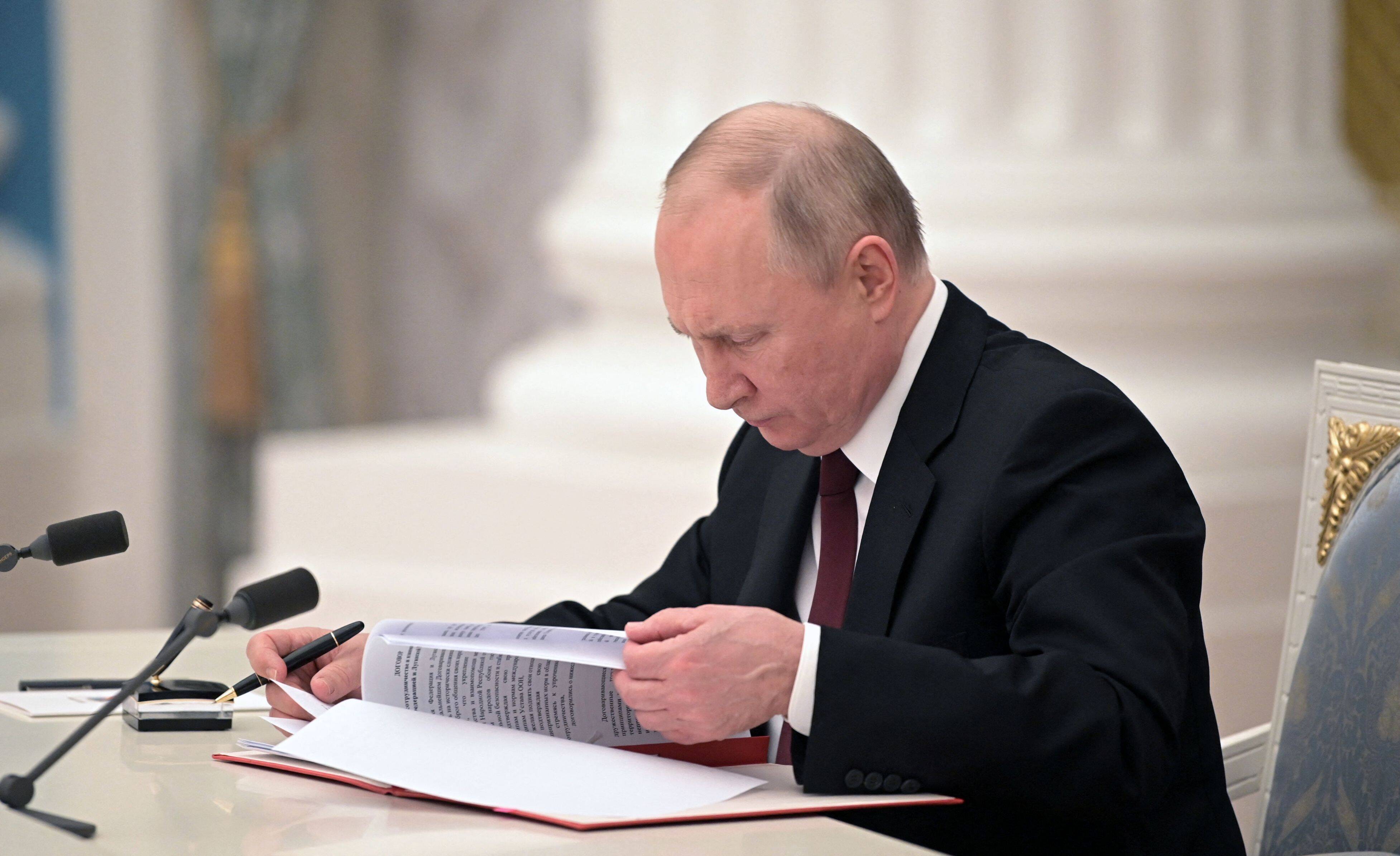Russian President Vladimir Putin signs documents, including a decree recognizing two Russian-backed breakaway regions in eastern Ukraine as independent, during a ceremony on Feb. 21 (Alexey Nikolsky/Sputnik/AFP)