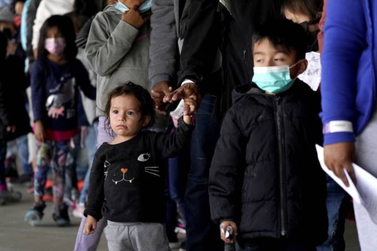 Migrant children along the U.S.-Mexico border are seen with adults as they wait in line to get a coronavirus test. (Julio Cortez/AP)